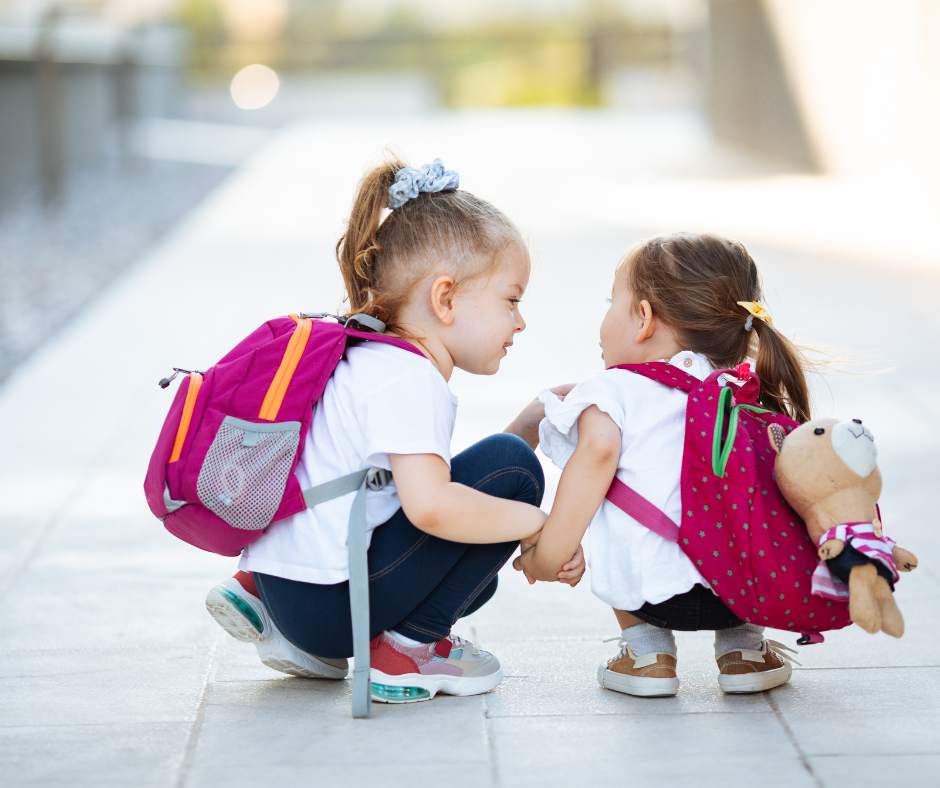 2 kleine Mädchen sitzen in der Hoche und schauen sich an