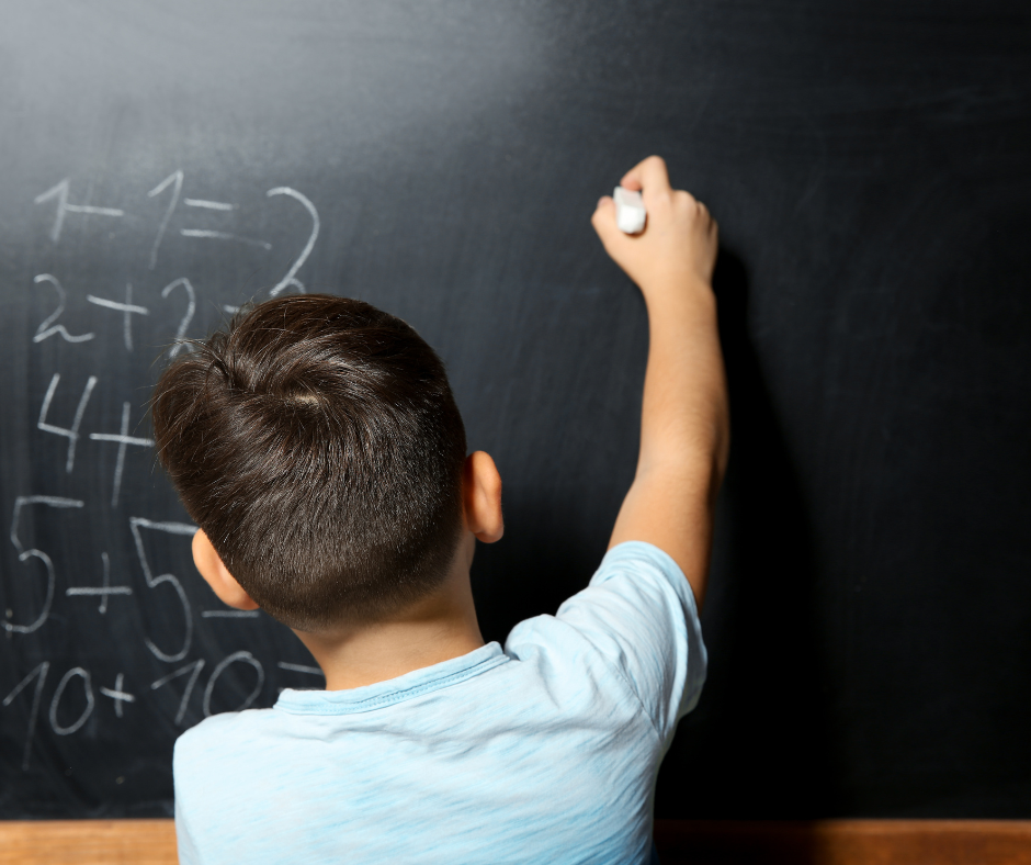 Junge an der Schultafel löst Matheaufgaben