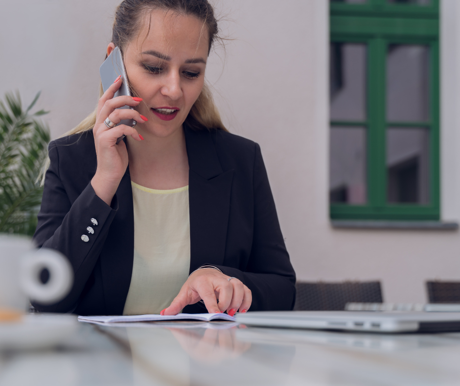 Frau am Telefon, die Unterlagen auf dem Tisch vor sich liegen hat